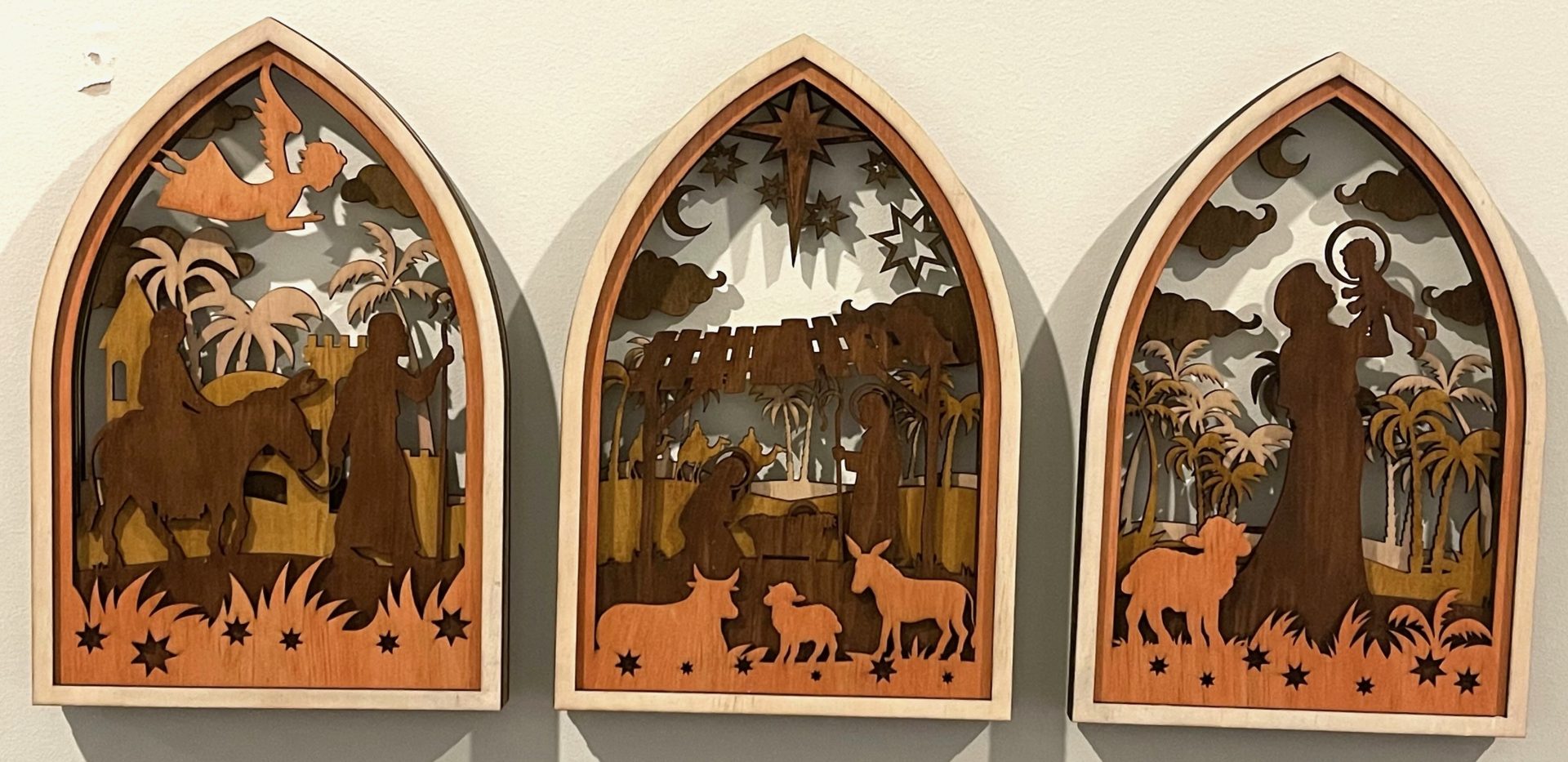 A Timeless Nativity: Laser-Cut Elegance Laser Cutting Project - This image showcases a beautifully crafted laser-cut Nativity scene triptych, perfect for adding a touch of elegance to your holiday décor. Each panel is intricately layered to depict the journey of Mary and Joseph, the birth of Jesus, and the adoration of the shepherds, all framed in a gothic-style arch. Ideal as a meaningful gift or a timeless addition to your own collection, this project is a must-try for laser cutting enthusiasts. Download the design files and instructions to create your own masterpiece.